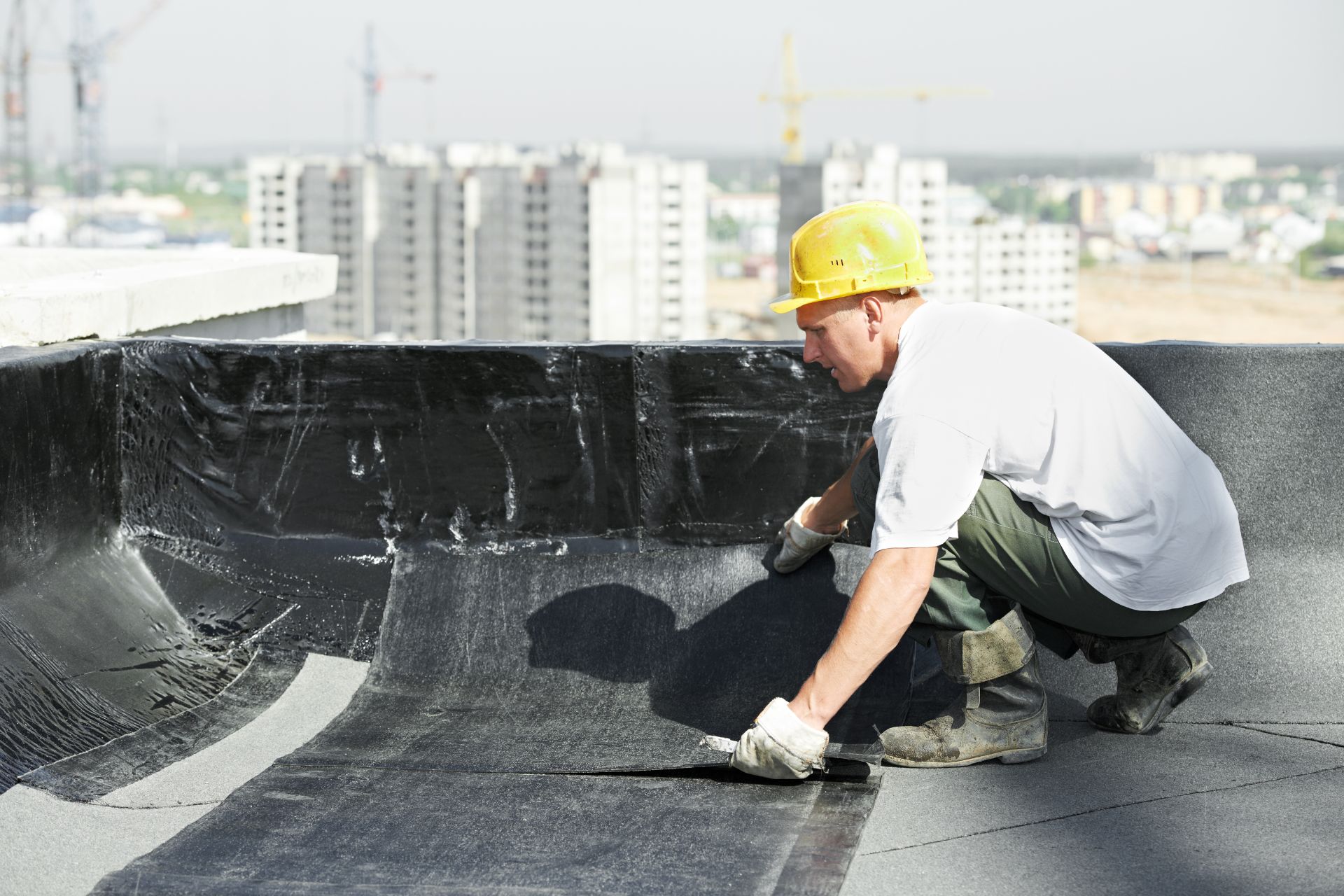 Stock photo of a worker applying modified bitumen roofing at a parapet edge